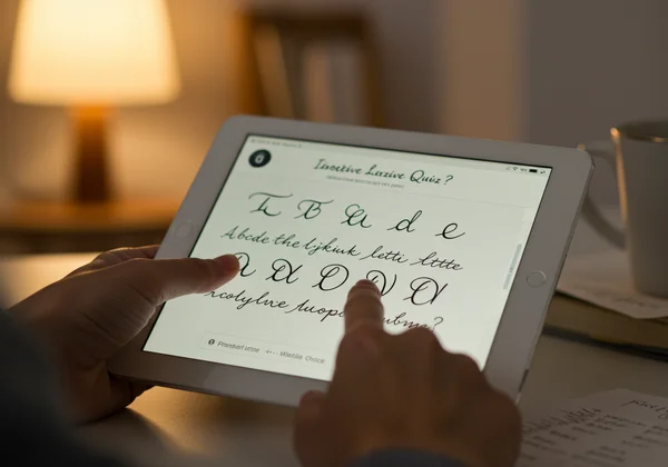 Person interacting with a cursive quiz on a tablet screen